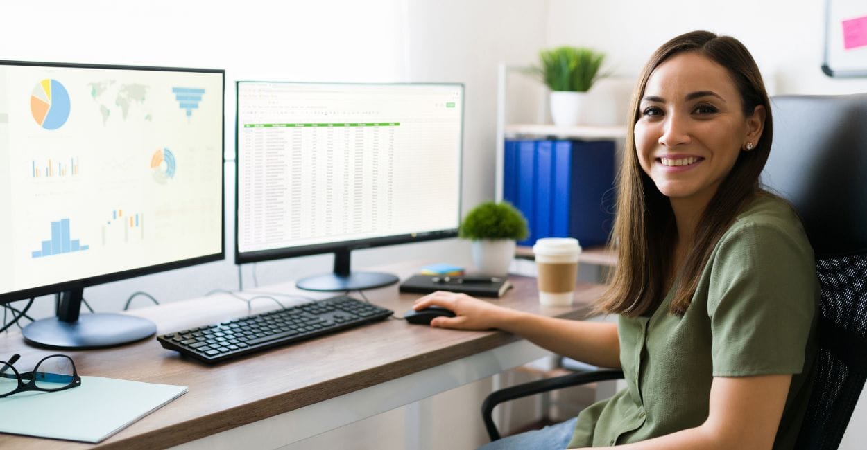 Mulher analisando gráficos no computador em ambiente de trabalho moderno